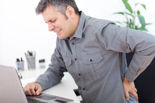 Sitting man experiencing back pain in need of chiropractic treatment.