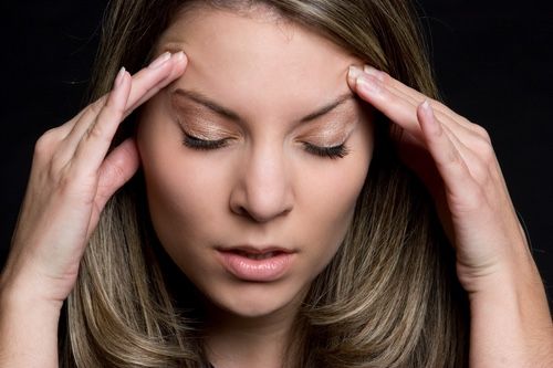 woman experiencing headache holds her temples